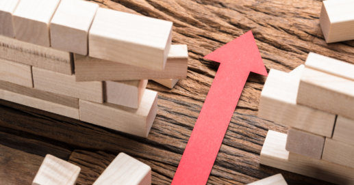 Red Paper Arrow Amidst Blocks On Wooden Table