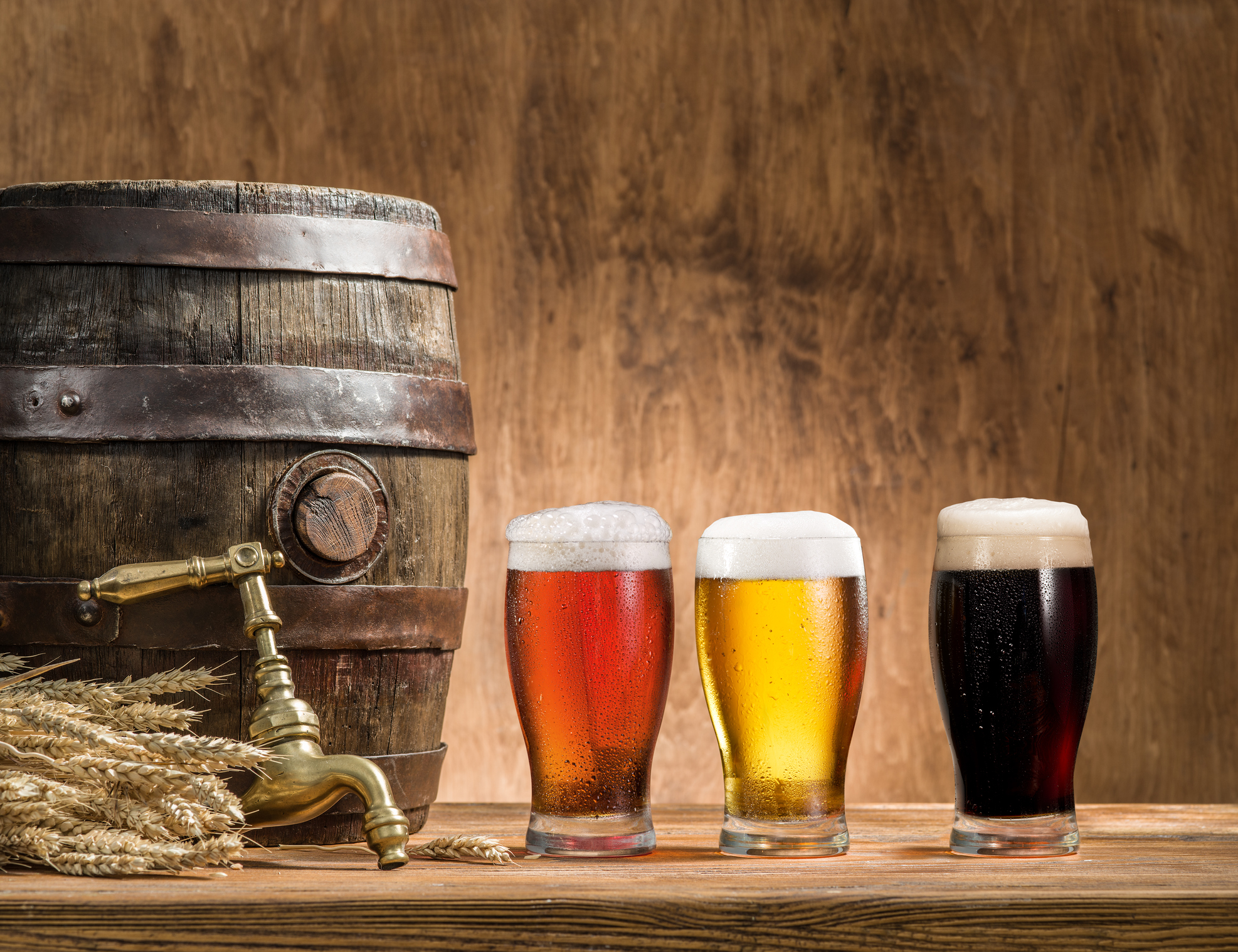 Glasses of beer and ale barrel on the wooden table.