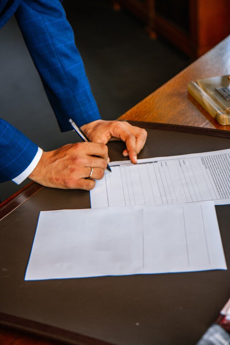 Photo of someone’s hands writing on a legal document Photo of someone's hands writing on a legal document