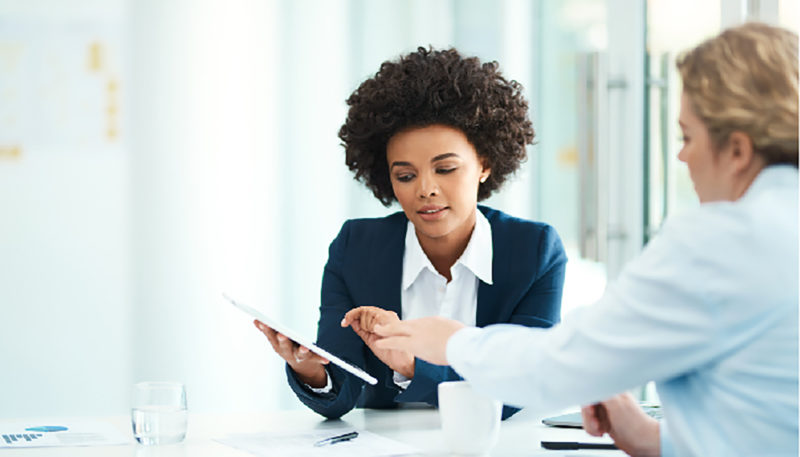 Two women co-workers look at an electronic tablet screen