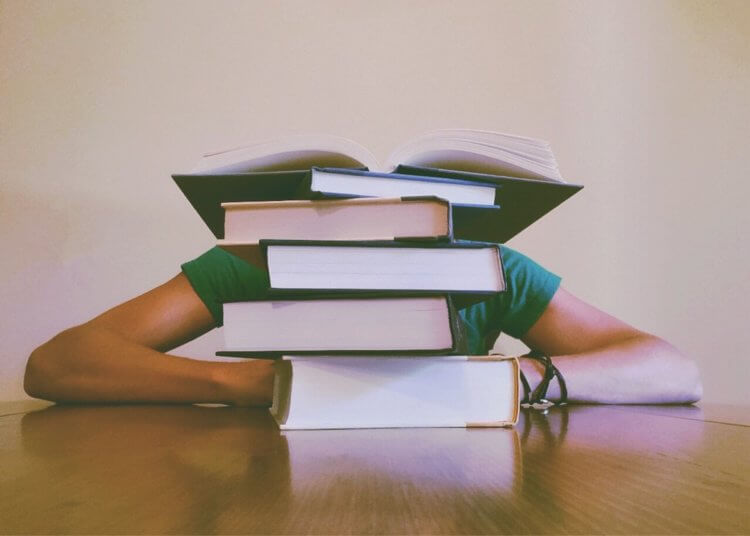 Person sitting behind stack of books Person sitting behind stack of books