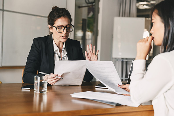 two women sitting at table discussing documents