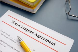 Non compete agreement NCA on a desk with a pen, notebooks and glasses