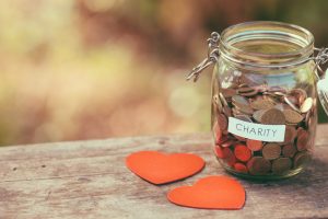 Money jar full of coins for charity and a couple of heart shapes