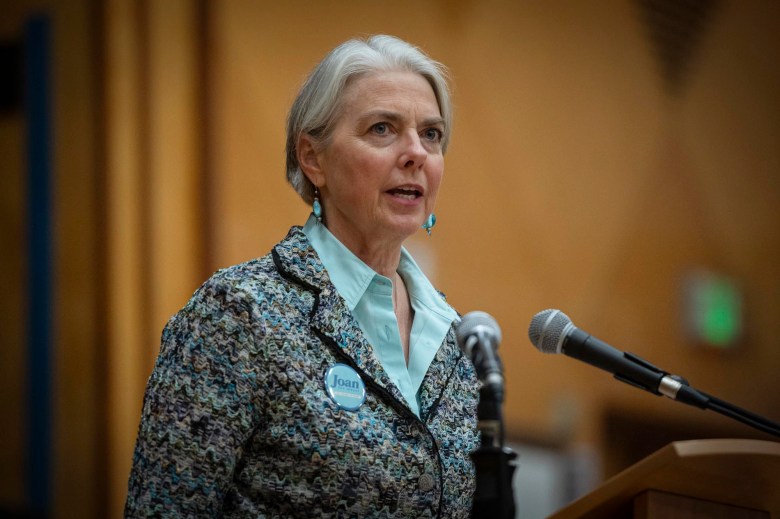 A woman speaking into a microphone at a podium.