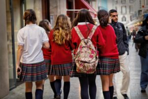 Photo showing the back of four girls walking down a street in school uniforms.