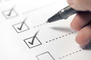 Hand with black pen marking on checklist box.