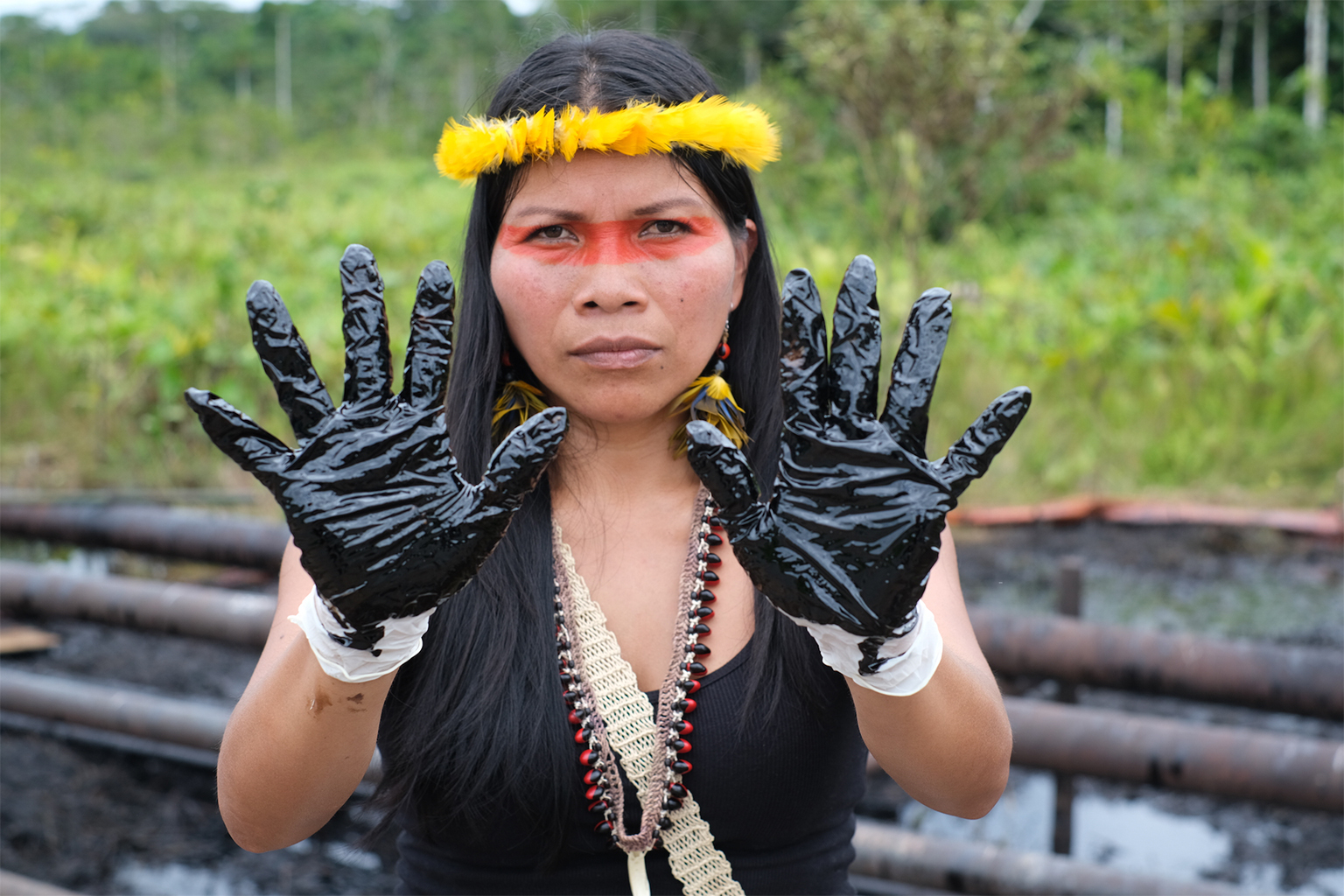 Waorani leader Nemonte Nenquimo stands next to an oil spill near Shushufindi